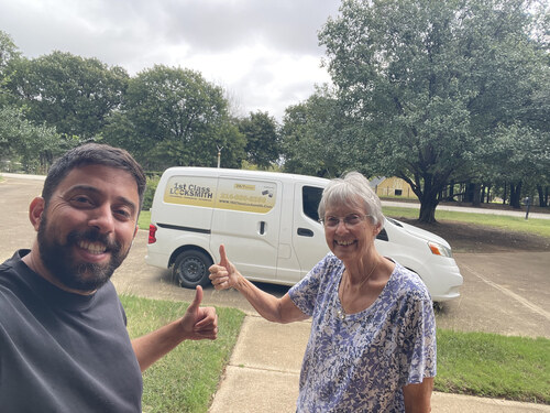 1st Class Locksmith Fort Worth technician smiling with a happy elderly customer after locksmith service, with a marked van in the background.